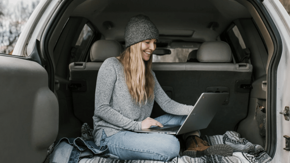 female digital nomad working in back of car