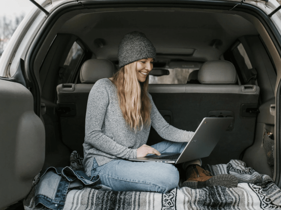 female digital nomad working in back of car