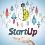 A hand holding underneath the words "Startup," surrounded by rocket ships and a lightbulb with a brain on one side of it.