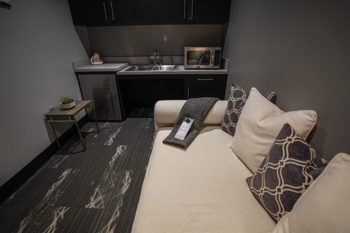 NuvoDesk Wellness Room with a couch, blanket, microwave, sink, and refrigerator.