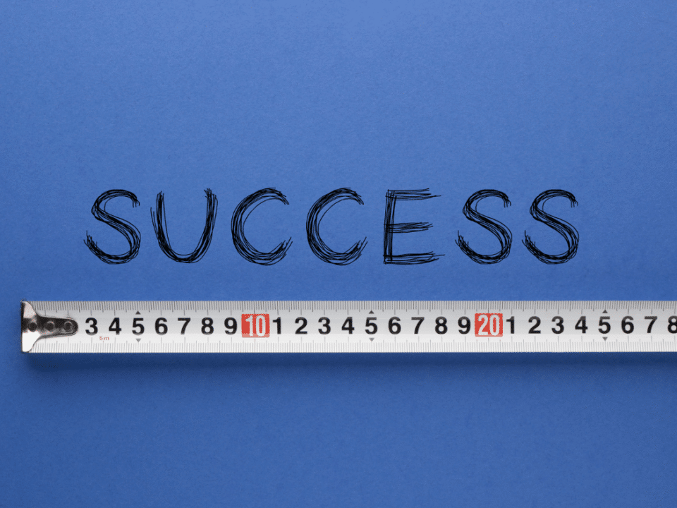 A white measuring tape is beneath the word "success," which is written and displayed on a dark blue background.