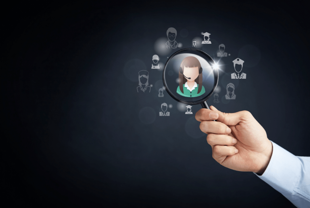 Person holding a magnifying glass that has a drawing of a person on it.