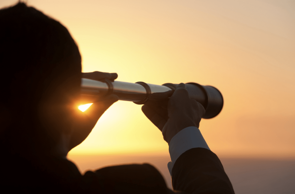 The Evolution of the Coworking Space: Silhouette of business man looking through spyglass