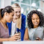 three diverse women in business looking at laptop
