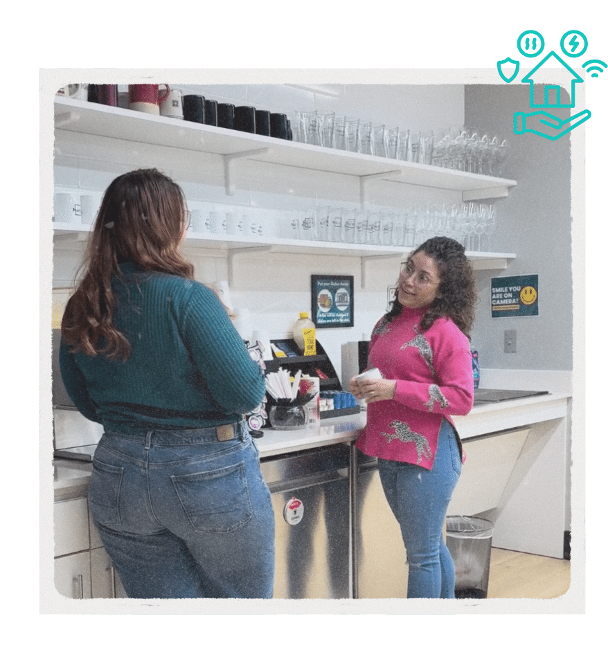 Two NuvoDesk members chatting and making coffee in the shared kitchen area, showcasing community and amenities.