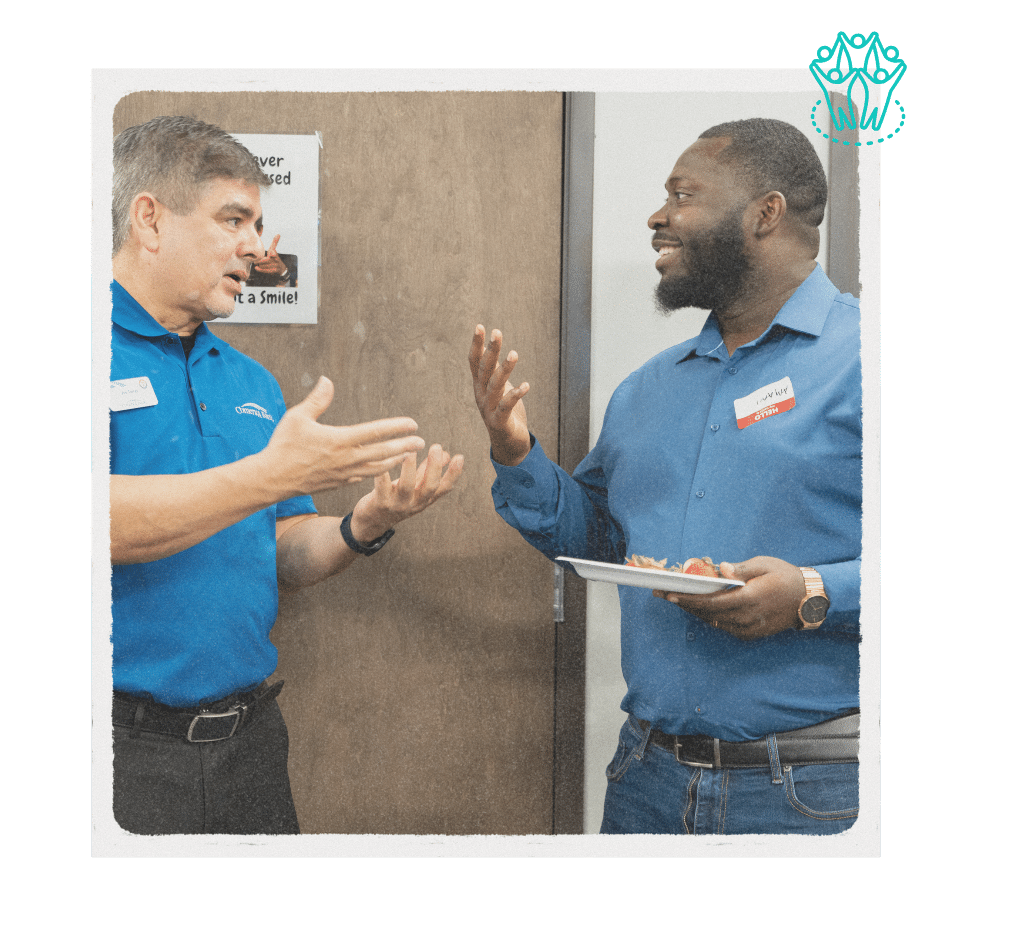  Two professionals networking and having a conversation at a NuvoDesk event, holding refreshments and wearing name tags.