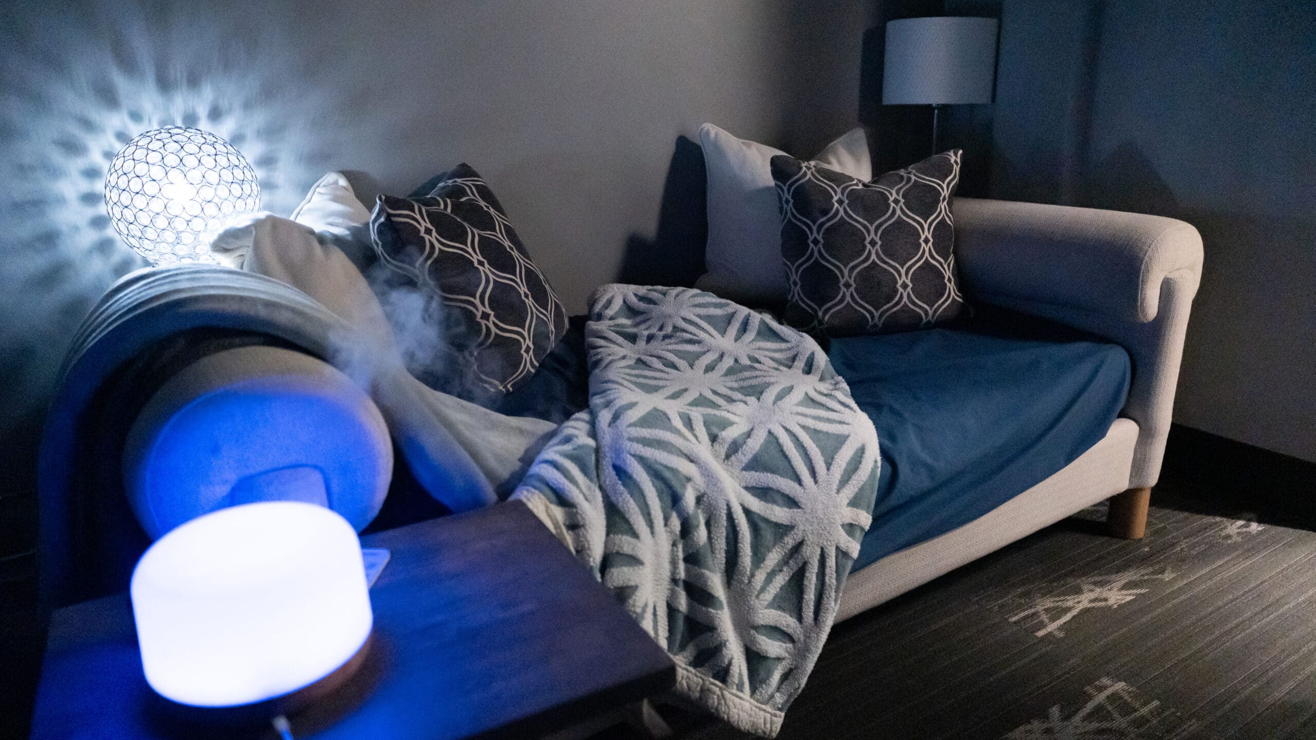 Relaxing Wellness Room at NuvoDesk Coworking ‣ NuvoDesk Coworking Cozy wellness room with sofa, blanket, pillows, and diffuser at NuvoDesk Coworking