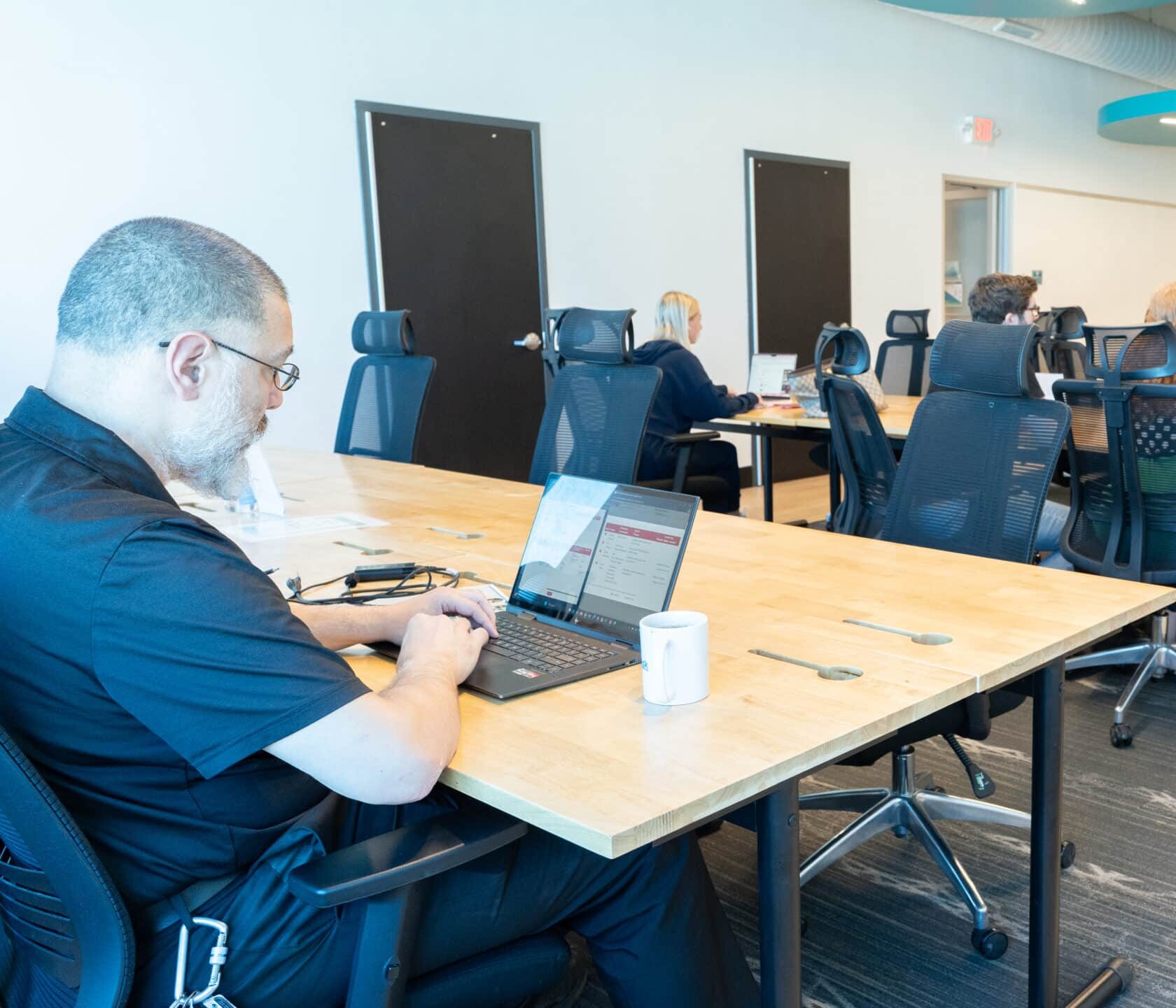 Professionals Working at NuvoDesk Shared Desk ‣ NuvoDesk Coworking People working on laptops at NuvoDesk Coworking shared desk area