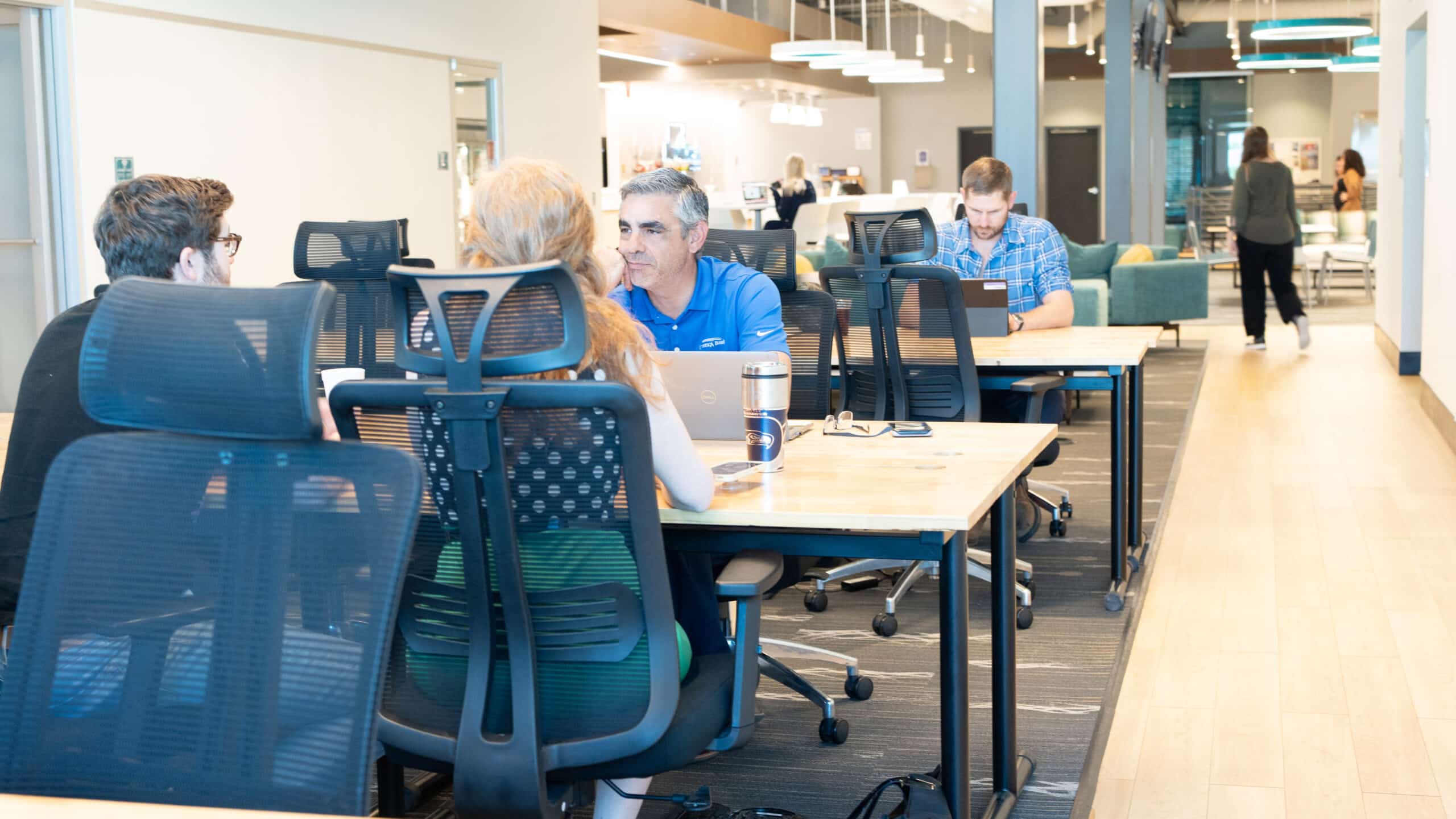 Collaboration at NuvoDesk Shared Desk Area ‣ NuvoDesk Coworking Group of coworkers collaborating at NuvoDesk Coworking shared desks